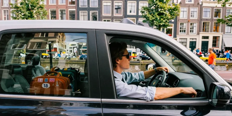 Taxi Amsterdam scène met een reiziger die geniet van de rit door de stadsstraten.